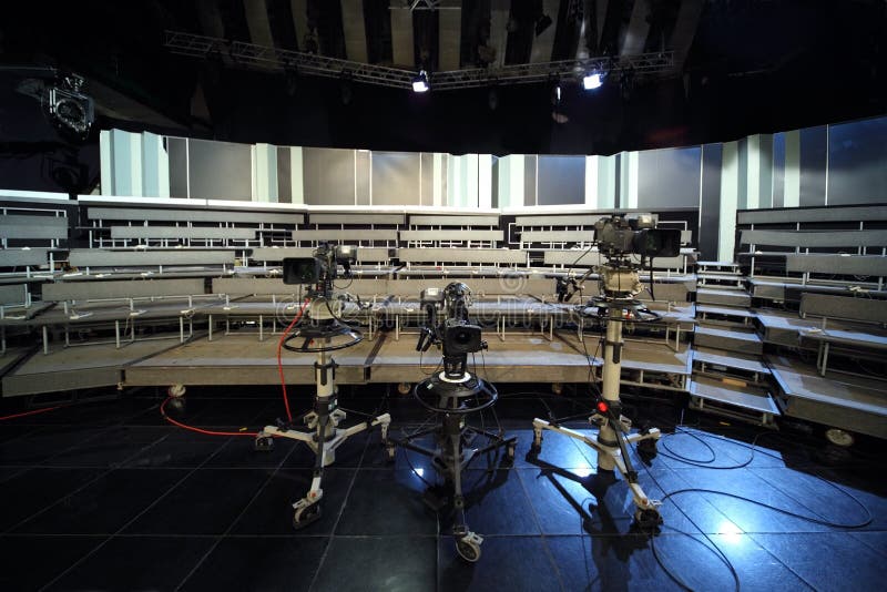 Three professional black video cameras in television studio, seats for audience. Three professional black video cameras in television studio, seats for audience