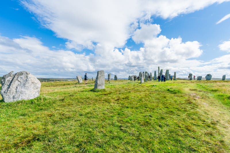 CALLANISH, ISLE OF LEWIS, SCOTLAND - AUGUST 03, 2022: Tourists visit Callanish standing stones site on the Isle of Lewis. The stones were erected in the late Neolithic era. CALLANISH, ISLE OF LEWIS, SCOTLAND - AUGUST 03, 2022: Tourists visit Callanish standing stones site on the Isle of Lewis. The stones were erected in the late Neolithic era