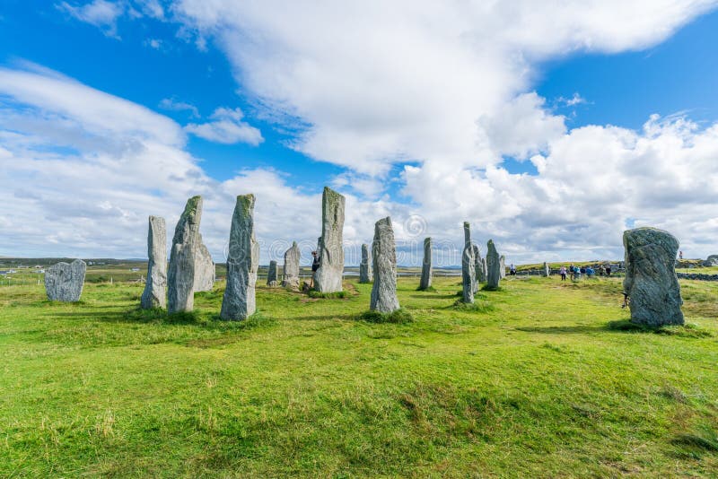 CALLANISH, ISLE OF LEWIS, SCOTLAND - AUGUST 03, 2022: Tourists visit Callanish standing stones site on the Isle of Lewis. The stones were erected in the late Neolithic era. CALLANISH, ISLE OF LEWIS, SCOTLAND - AUGUST 03, 2022: Tourists visit Callanish standing stones site on the Isle of Lewis. The stones were erected in the late Neolithic era