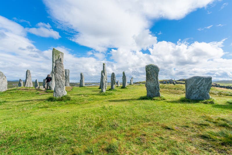 CALLANISH, ISLE OF LEWIS, SCOTLAND - AUGUST 03, 2022: Tourists visit Callanish standing stones site on the Isle of Lewis. The stones were erected in the late Neolithic era. CALLANISH, ISLE OF LEWIS, SCOTLAND - AUGUST 03, 2022: Tourists visit Callanish standing stones site on the Isle of Lewis. The stones were erected in the late Neolithic era