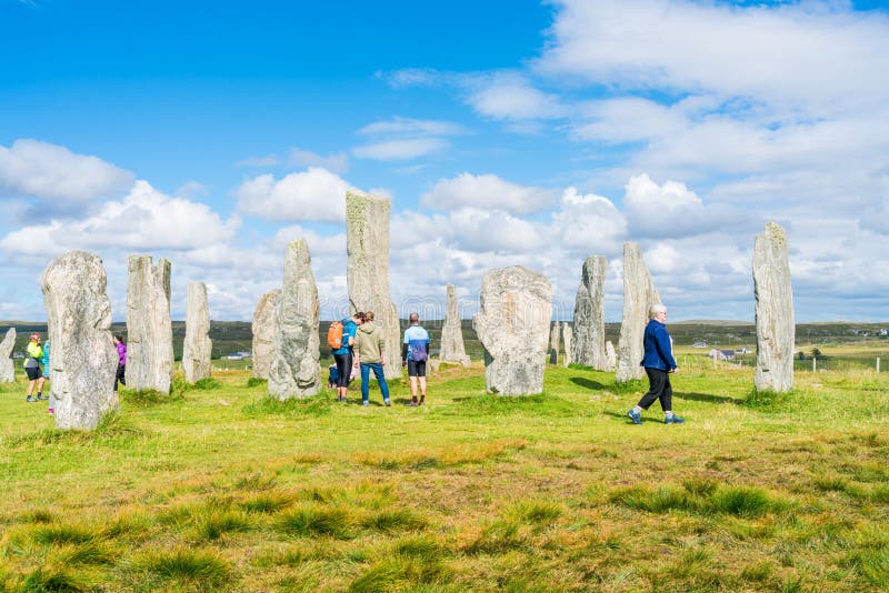 CALLANISH, ISLE OF LEWIS, SCOTLAND - AUGUST 03, 2022: Tourists visit Callanish standing stones site on the Isle of Lewis. The stones were erected in the late Neolithic era. CALLANISH, ISLE OF LEWIS, SCOTLAND - AUGUST 03, 2022: Tourists visit Callanish standing stones site on the Isle of Lewis. The stones were erected in the late Neolithic era