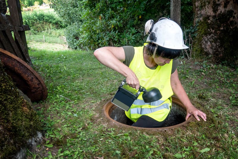 Kanał ściekowy naprawa pracuje w manhole kobieta pracownikiem obrazy stock Kanał ściekowy naprawa pracuje w manhole kobieta pracownikiem obrazy stock