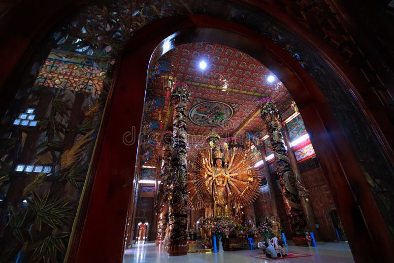 Take photo man and woman with large Guan Yin Bodhisattva carved from wood 12 meters high in Wat Metta Photiyan