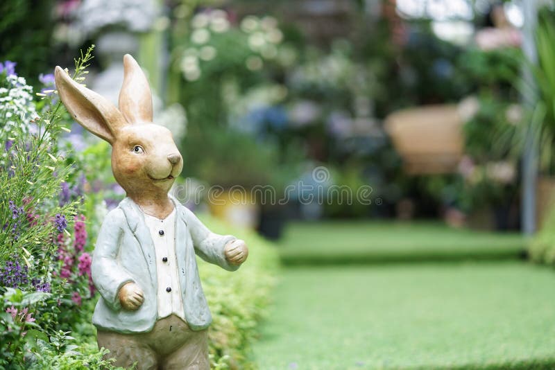 Kaninchenstatue Eine süße Kaninchen-Holzstatue mit einem blauen Anzug für Gartendekoration stockfotografie