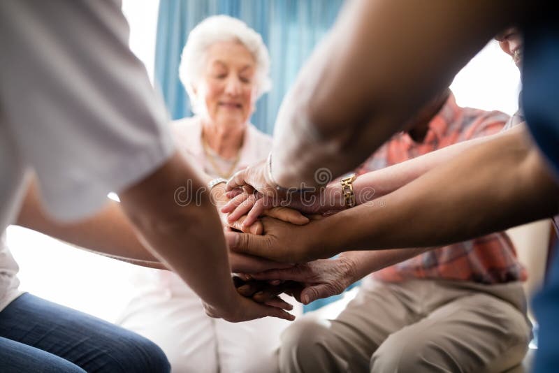 Kantjusterad bild av kvinnligt doktors- och pensionärfolk som staplar händer arkivfoto Kantjusterad bild av kvinnligt doktors- och pensionärfolk som staplar händer arkivfoto