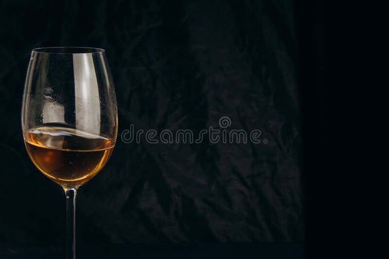 Kantjusterad kvinnlig hand som rymmer ett exponeringsglas av vitt vin på en svart bakgrund r alkoholdryckcloseup arkivfoto Kantjusterad kvinnlig hand som rymmer ett exponeringsglas av vitt vin på en svart bakgrund r alkoholdryckcloseup arkivfoto