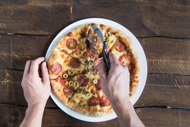 Kantjusterat skott av personen som klipper läcker ny pizza royaltyfri foto Kantjusterat skott av personen som klipper läcker ny pizza royaltyfri foto