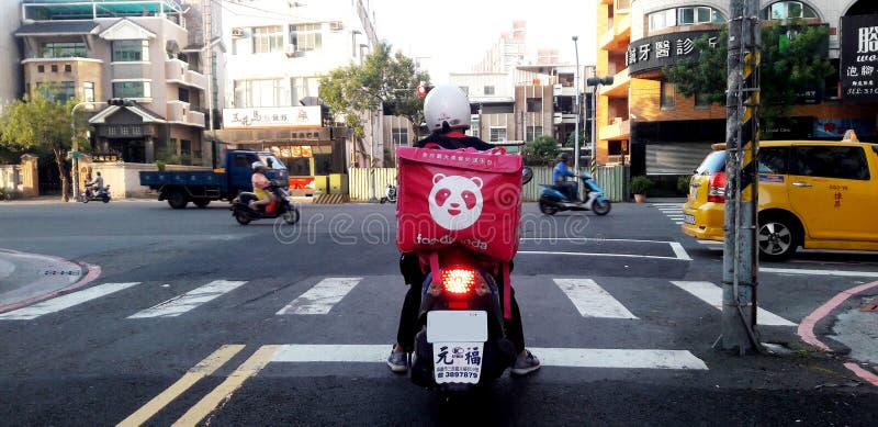 Kaohsiung, Taiwan, November 10, 2019: A (foodpanda) motorcycle stopped at the exit of the road waiting for traffic lights. Foodpanda is a popular food delivery service.