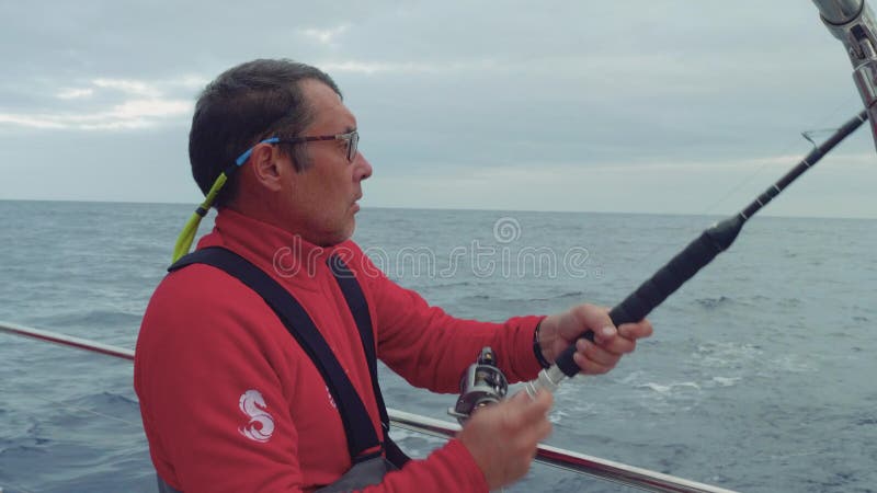 Kappseglaren fiska med drag i fisken från bräde av yachtseglingen i havet