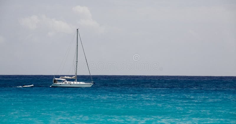 A lone sailboat floats in the waters near Maho Bay off the beautiful Caribbean island of St. Maarten. A lone sailboat floats in the waters near Maho Bay off the beautiful Caribbean island of St. Maarten.