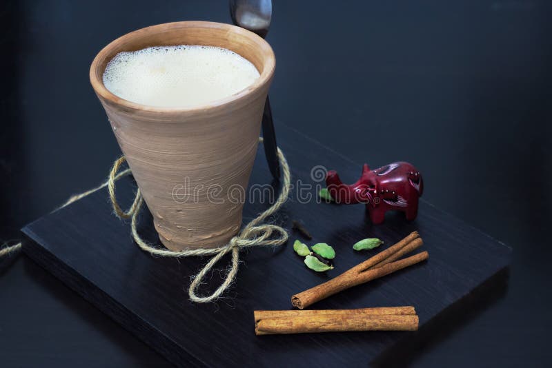 Karak indio del té de chai del masala con las especias y la leche, en vidrio de la arcilla Fondo de madera negro imagen de archivo libre de regalías Karak indio del té de chai del masala con las especias y la leche, en vidrio de la arcilla Fondo de madera negro imagen de archivo libre de regalías