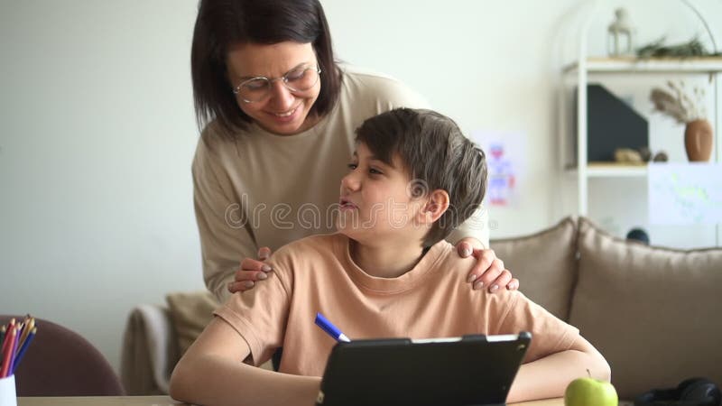 Karantän för hemfolk : skolpojkstudier online vid bord med tablett och har tid med mamma spbd. lager videofilmer