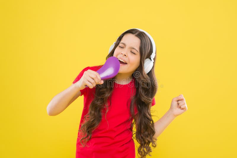 Karaokestjärna Gullig liten flicka som låtsar sjunga karaoke på gul bakgrund Förtjusande barn som utför karaokesång royaltyfri foto Karaokestjärna Gullig liten flicka som låtsar sjunga karaoke på gul bakgrund Förtjusande barn som utför karaokesång royaltyfri foto