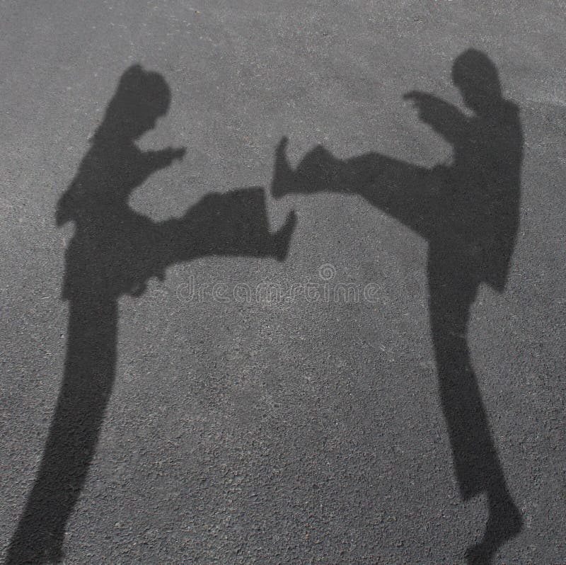 Karate children in a competitive combat as the cast shadow of a girl and boy fighting with leg kicks as martial arts for kid fitness and healthy activities symbol. Karate children in a competitive combat as the cast shadow of a girl and boy fighting with leg kicks as martial arts for kid fitness and healthy activities symbol.