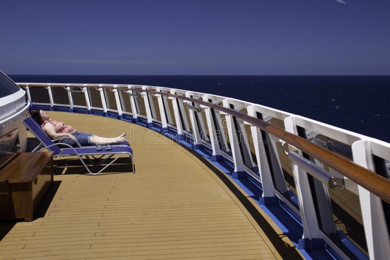 A single lounge chair tempts a world weary passenger to find some peace and quiet and relax and soak up the Caribbean sun as they lay out in lounge chairs on the deck of the Carnival Dream. A single lounge chair tempts a world weary passenger to find some peace and quiet and relax and soak up the Caribbean sun as they lay out in lounge chairs on the deck of the Carnival Dream.