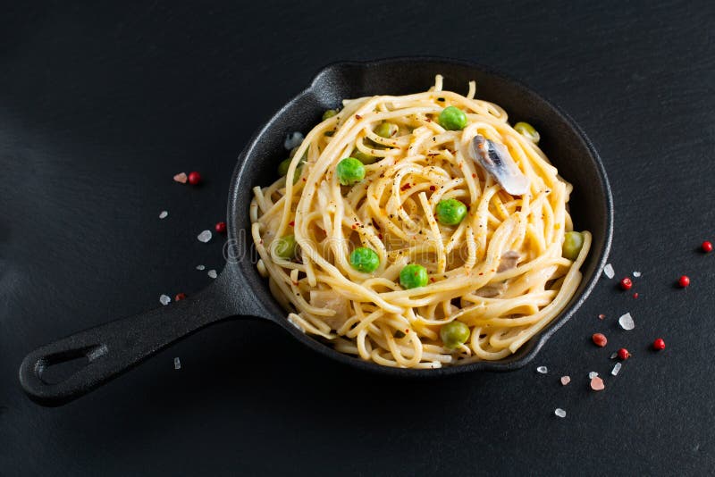 Karmowego pojęcia domowej roboty spaghetti śmietankowy - biały kumberland w żeliwnej rynienki niecce na łupku kamieniu zdjęcie royalty free Karmowego pojęcia domowej roboty spaghetti śmietankowy - biały kumberland w żeliwnej rynienki niecce na łupku kamieniu zdjęcie royalty free