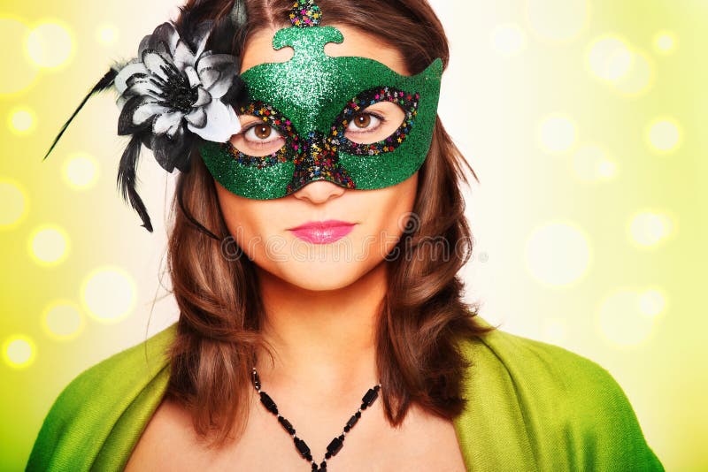 A picture of a young woman wearing a carnival mask over green background. A picture of a young woman wearing a carnival mask over green background