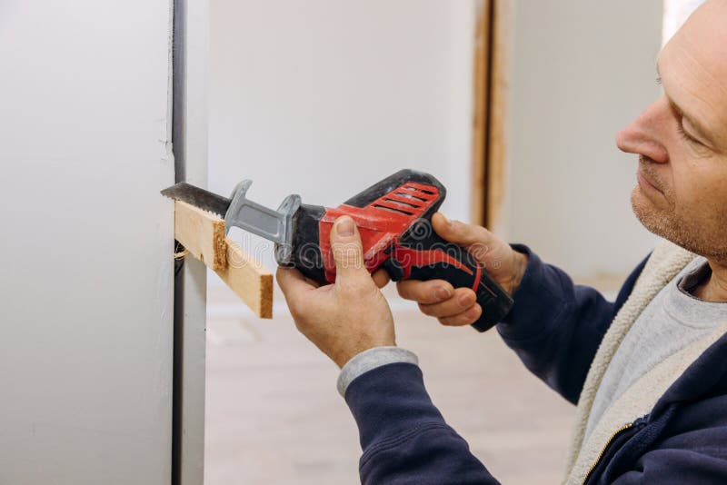 Carpenter using hackzall for cutting wooden plank construction details of installing a wooden beam cased opening walkway between rooms carpentry tools. Carpenter using hackzall for cutting wooden plank construction details of installing a wooden beam cased opening walkway between rooms carpentry tools