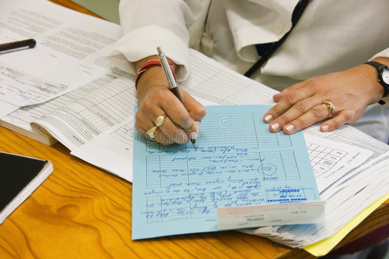 Female doctor writing a file for a patient in the hospital. Female doctor writing a file for a patient in the hospital