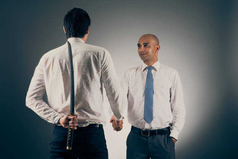 Businessman shaking hands with his partner while hiding katana sword behind his back. Businessman shaking hands with his partner while hiding katana sword behind his back