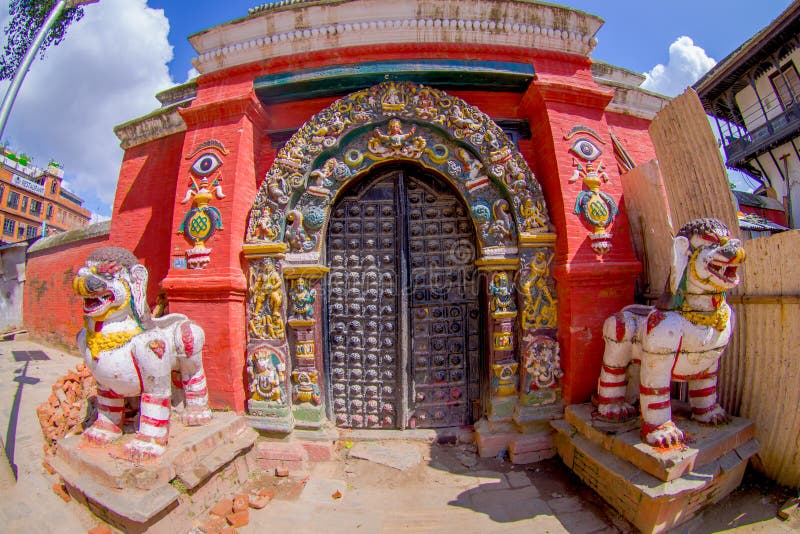 KATHMANDU, NEPAL OCTOBER 15, 2017: Close up of two stoned guardians an the enter of a temple, with some carved structure in the the door and frame of the enter of the building, in reconstruction after the earthquake in 2015 of Durbar square in Kathmandu, capital of Nepal. KATHMANDU, NEPAL OCTOBER 15, 2017: Close up of two stoned guardians an the enter of a temple, with some carved structure in the the door and frame of the enter of the building, in reconstruction after the earthquake in 2015 of Durbar square in Kathmandu, capital of Nepal.