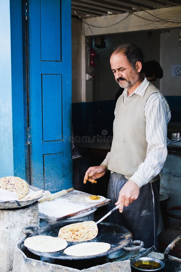 KATMANDU, NEPAL - ABRIL DE 2015: cocinero que hace el pan del roti en su tienda abierta de la calle foto de archivo KATMANDU, NEPAL - ABRIL DE 2015: cocinero que hace el pan del roti en su tienda abierta de la calle foto de archivo