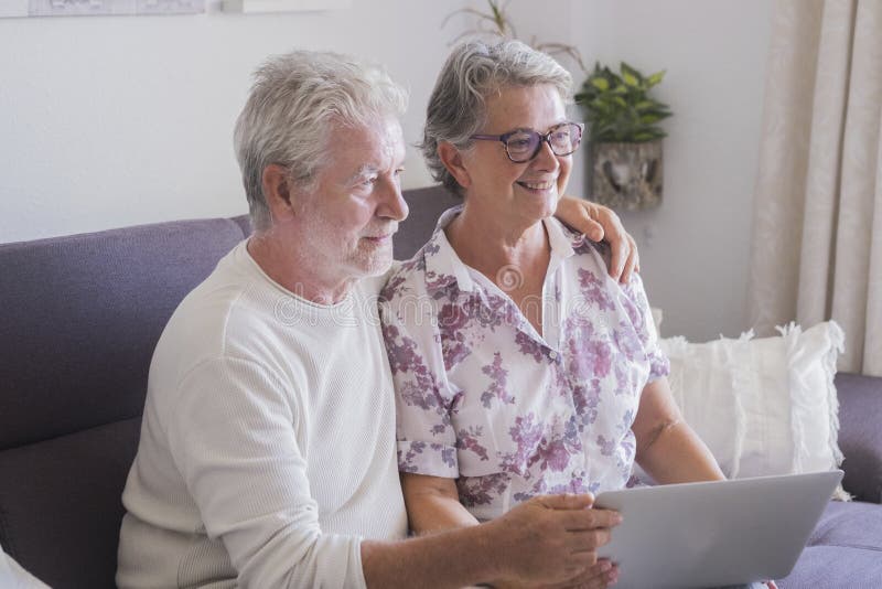 Kaukasisch mooi paar van bejaarde hogere volwassene die thuis Internet met laptop gebruiken samen - Internet voor gepensioneerden royalty-vrije stock fotografie Kaukasisch mooi paar van bejaarde hogere volwassene die thuis Internet met laptop gebruiken samen - Internet voor gepensioneerden royalty-vrije stock fotografie