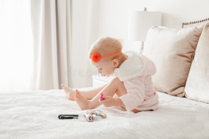 Kaukasische Babymalerei nagelt auf Bett zu Hause sitzen stockbild Kaukasische Babymalerei nagelt auf Bett zu Hause sitzen stockbild
