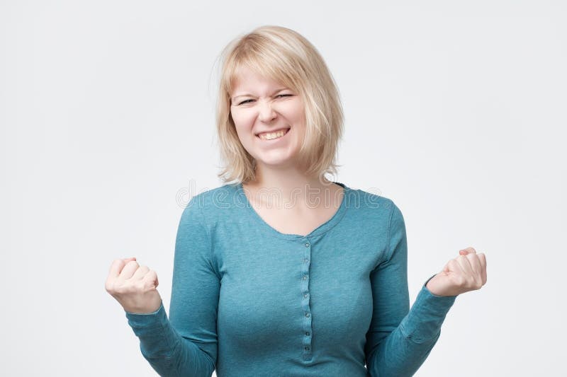 Kaukasische blondevrouw die zich haar succes en overwinning verheugen die haar vuisten met vreugde dichtklemmen royalty-vrije stock foto's Kaukasische blondevrouw die zich haar succes en overwinning verheugen die haar vuisten met vreugde dichtklemmen royalty-vrije stock foto's