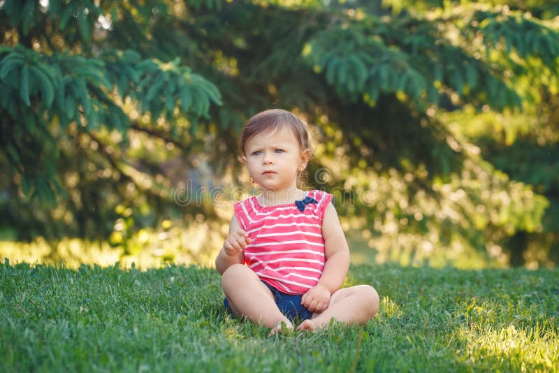 Kaukasische de peuterzitting van het babymeisje in park buiten stock afbeeldingen Kaukasische de peuterzitting van het babymeisje in park buiten stock afbeeldingen