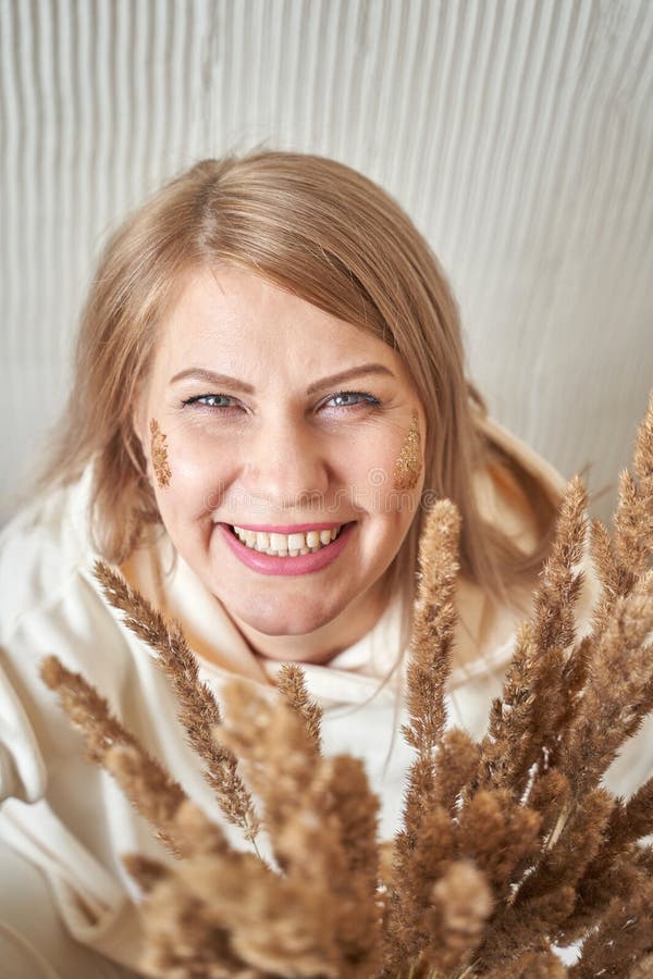 Kaukasische erwachsene Frau lächelnd mit getrockneten Weizenhalden und natürlichem Make-up drinnen stockbilder