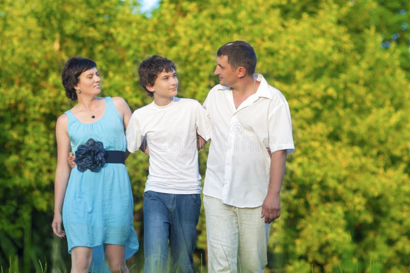 Kaukasische Familie van Drie die een Gang samen in Omhelst Park hebben stock afbeelding Kaukasische Familie van Drie die een Gang samen in Omhelst Park hebben stock afbeelding
