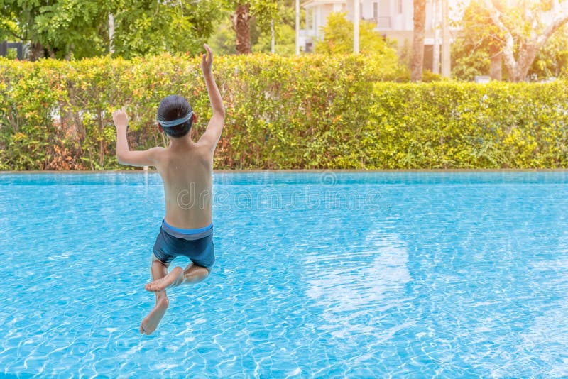 Kaukasische jongen die pret hebben die in de pool springen Gelukkig jongensjong geitje die in de pool springen stock foto Kaukasische jongen die pret hebben die in de pool springen Gelukkig jongensjong geitje die in de pool springen stock foto