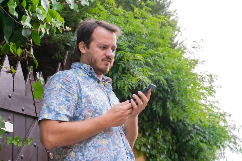 Kaukasische man die op een slimme telefoon kijkt met uitdrukking van verwondering en verward, die een e-mail leest Ernstige man w stock fotografie Kaukasische man die op een slimme telefoon kijkt met uitdrukking van verwondering en verward, die een e-mail leest Ernstige man w stock fotografie