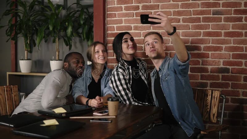 Kaukasische mens die groep nemen selfie op vergadering met diverse vrienden in coffeeshop of werkplaats, multiraciale jongeren