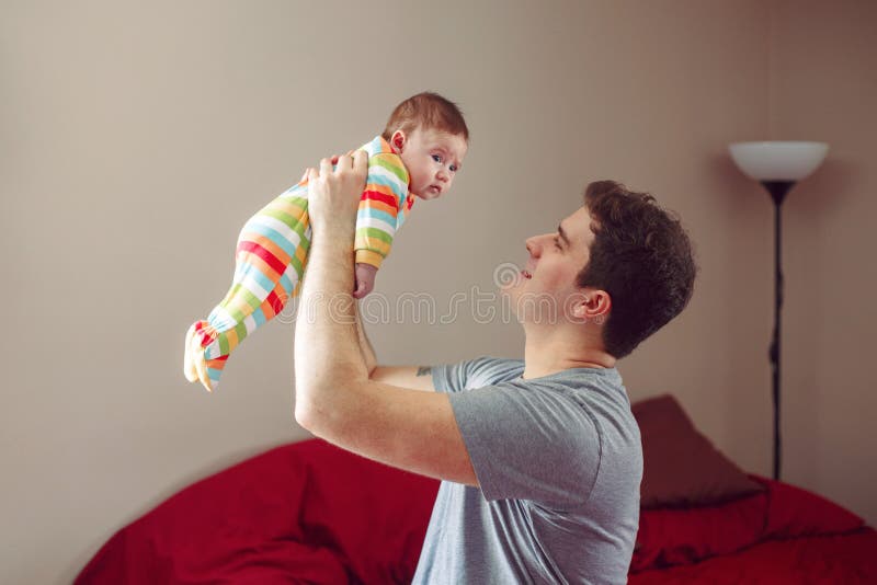 Kaukasische vader die en het glimlachen aan pasgeboren baby koesteren spreken Mannelijk de holdingskind van de mensenouder stock foto's Kaukasische vader die en het glimlachen aan pasgeboren baby koesteren spreken Mannelijk de holdingskind van de mensenouder stock foto's