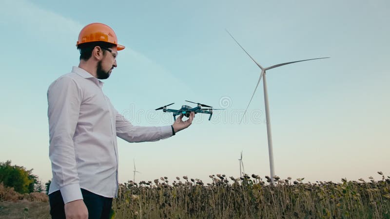 Kaukasischer Ingenieur in einem orange Schutzhelm setzt an Schutzbrillen und startet ein intelligentes quadrocopter Brummen von s stock video footage