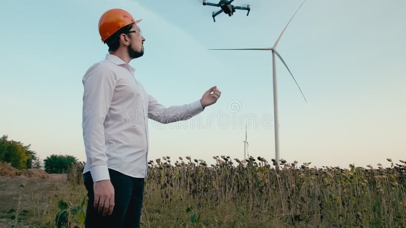 Kaukasischer Ingenieur in einem orange Schutzhelm und in den Schutzbrillen startet von seiner Hand ein intelligentes quadcopter B stock video