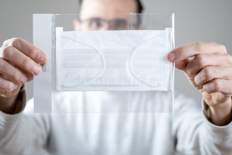 Kaukasischer Mann, der eine weiße medizinische Maske im Paket für den Schutz gegen ansteckende Krankheit Coronavirus hält lizenzfreies stockfoto