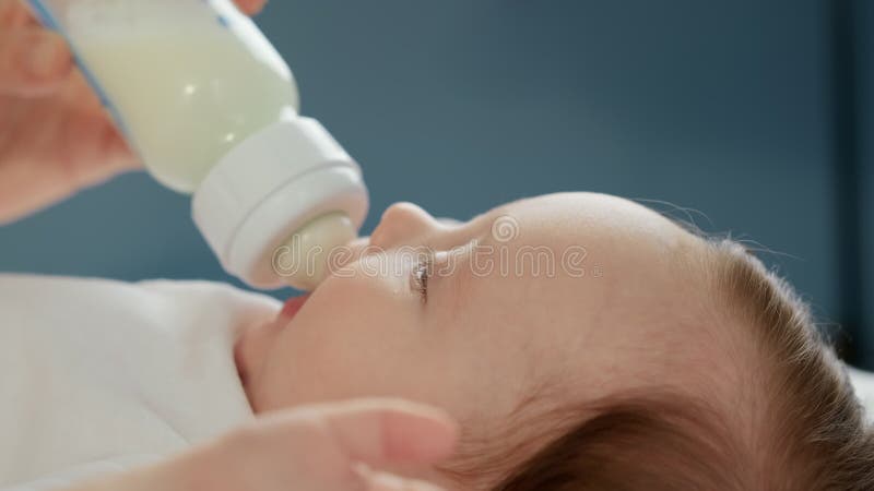 Kaukasisches Neugeborenes trinkt Mütter Milch aus kleinen Plastik-Babyflasche durch Schnuller. Porträt