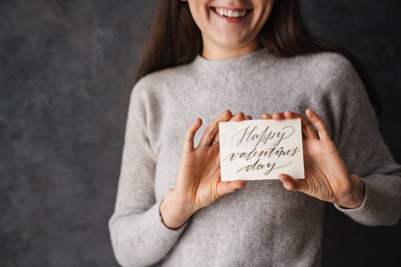 Kaukasisk leende flicka som visar lyckliga valentinekort inom kameran fotografering för bildbyråer