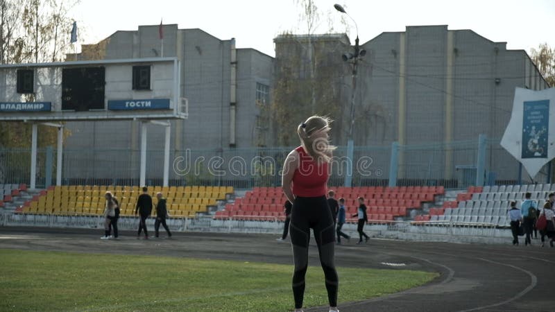 Kaukasisk söt kvinna som står på stadion framför gruppen skolbarn