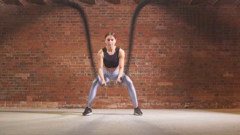 Kaukaska dysponowana kobieta ćwiczy z batalistycznymi arkanami przy gym