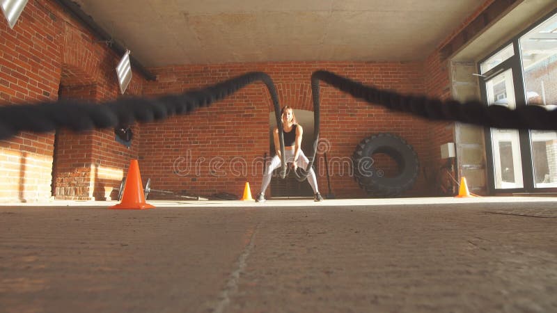 Kaukaska dysponowana kobieta ćwiczy z batalistycznymi arkanami przy gym