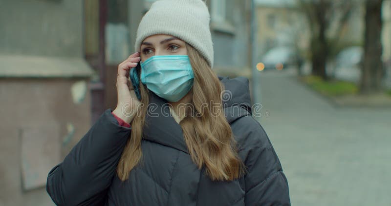 Kaukaska młoda stylowa kobieta w masce ochronnej rozmawiająca przez komórkę na ulicy. piękna szczęśliwa kobieta