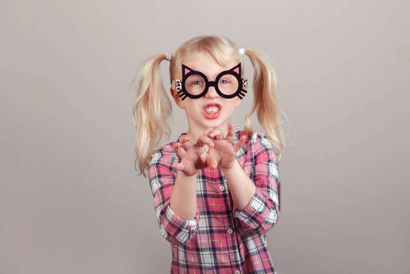 Closeup portrait of cute adorable blonde Caucasian preschool girl wearing funny cat glasses and playing, acting, making faces. Kid expressing emotions. April fool`s day concept. Closeup portrait of cute adorable blonde Caucasian preschool girl wearing funny cat glasses and playing, acting, making faces. Kid expressing emotions. April fool`s day concept