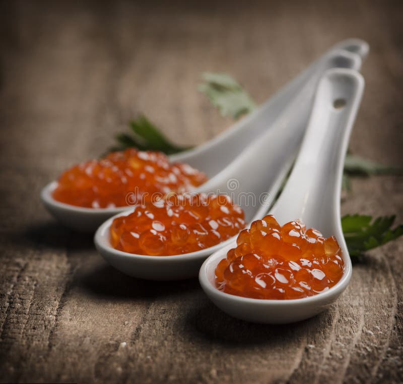 Caviar in white spoon on wooden table. Caviar in white spoon on wooden table