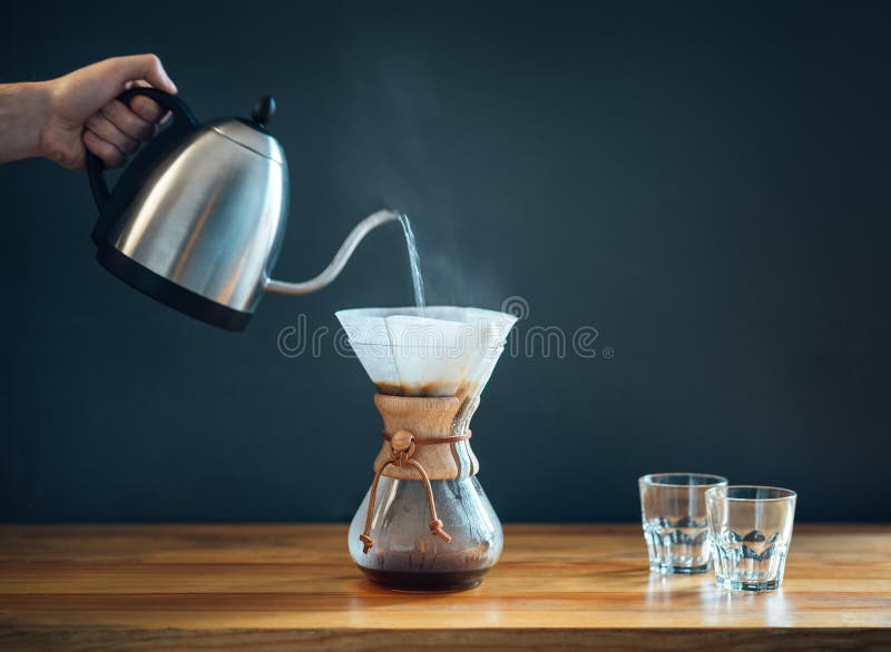 Kawa przy użyciu alternatywnej metody, wlewając gorącą wodę z czajnika do szklanego dekantu na drewnianym stole