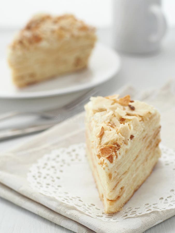 Kawałek wielo- płatowaty tortowy zakończenie Mille feuille deser Kruszki dekorowali torte na białym doily na drewnianego stół obrazy royalty free Kawałek wielo- płatowaty tortowy zakończenie Mille feuille deser Kruszki dekorowali torte na białym doily na drewnianego stół obrazy royalty free