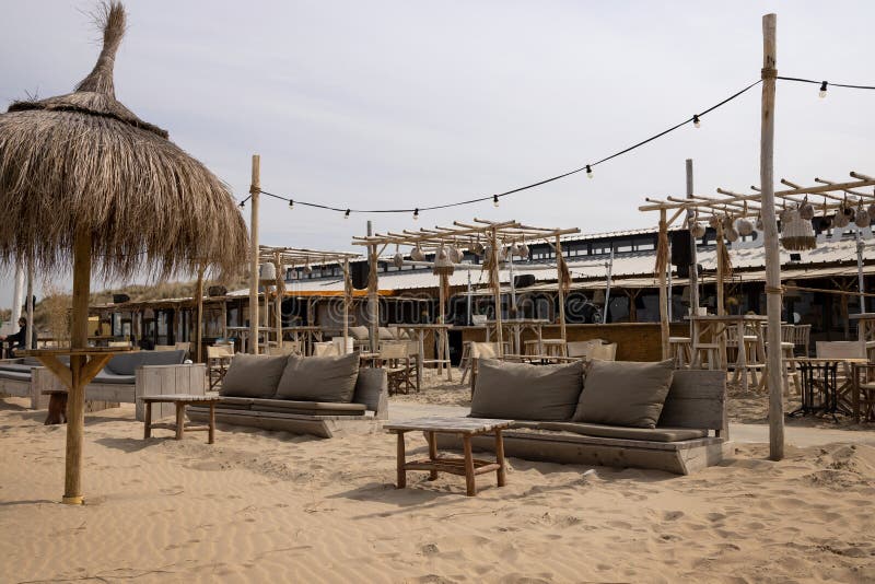 Cafe on the sea sandy beach with reed umbrellas, wooden armchairs and tables, pergolas and lanterns. Cafe on the sea sandy beach with reed umbrellas, wooden armchairs and tables, pergolas and lanterns